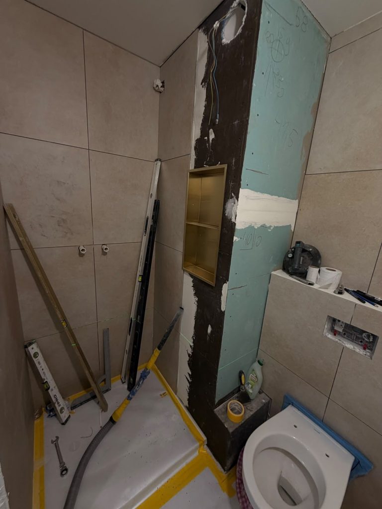 Układanie płytek w łazience z wnęką ze złotym wykończeniem