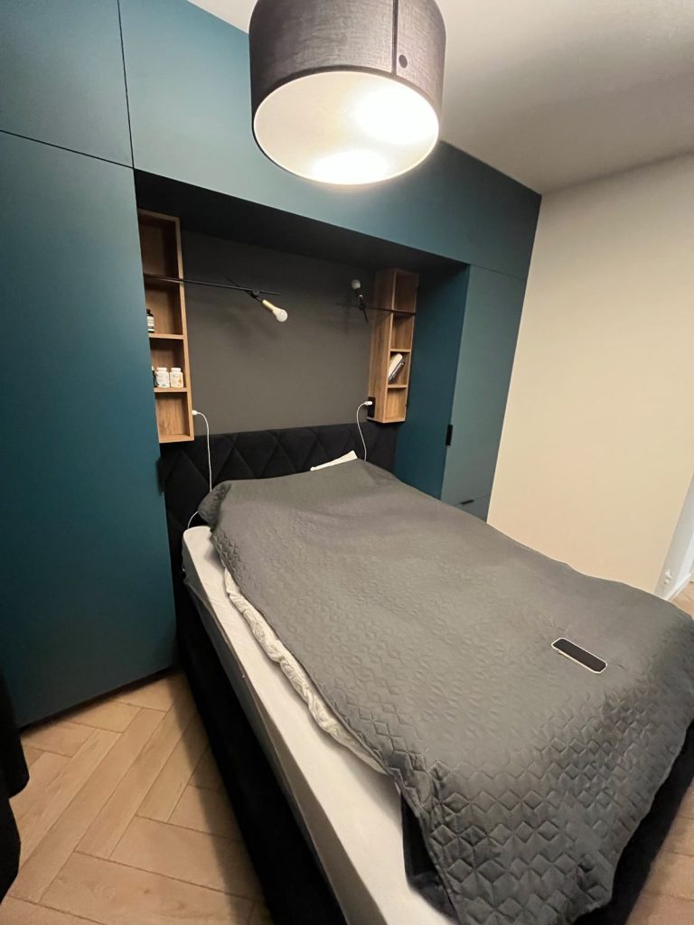 Sypialnia z turkusową zabudową i lampą wiszącą