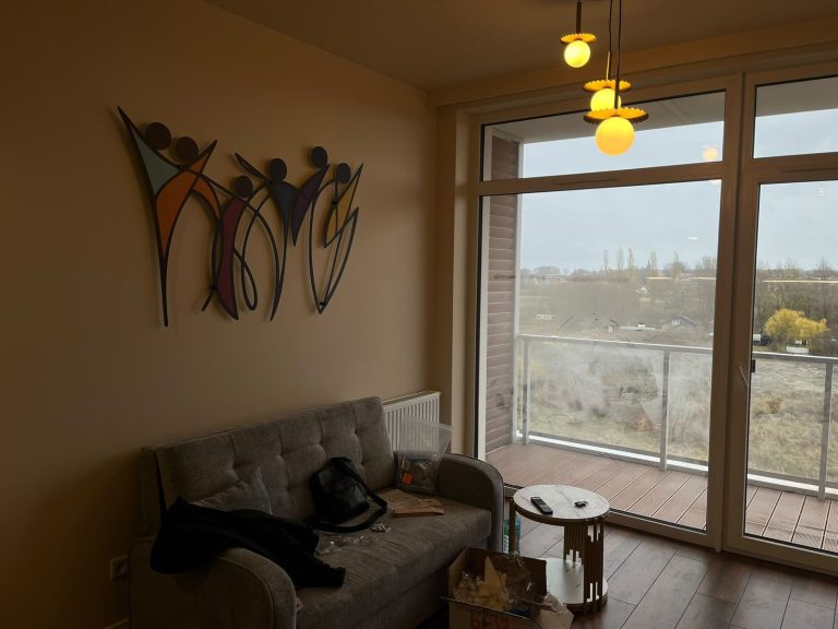 Salon z dekoracją ścienną i wyjściem na balkon
